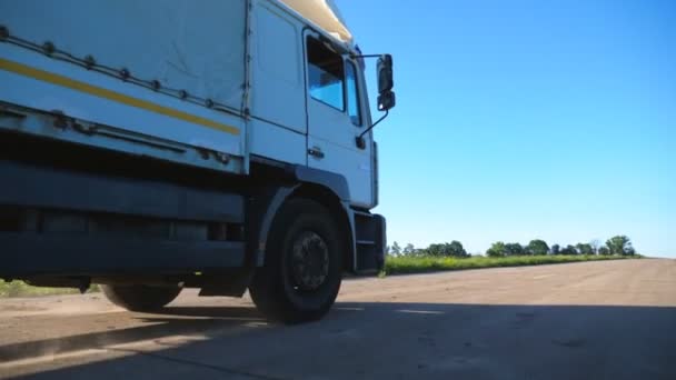 Zijaanzicht van vrachtwagen met vrachtauto rijden langs lege snelweg en het vervoer van goederen. Vrachtwagen rijden naar bestemming via het platteland weg. Vrachtvervoer concept. Langzame beweging — Stockvideo