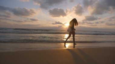 Yürüyüş ve Okyanusu yakınlarındaki sahilde oynarken mutlu bir kadın. Genç güzel kız hayattan zevk ve deniz sahilinde eğleniyor. Yaz tatili ya da tatil. Arka plan egzotik manzaraya. Ağır çekim