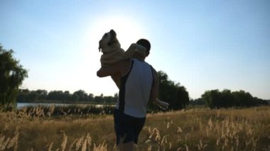 Ellerinde alan köpeği taşıyan bir genç adam. Labrador veya doğa adlı golden retriever oynuyor. Sevgi ve dostluk ile evcil hayvan. Yavaş hareket kapatmak