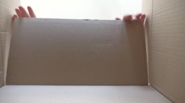 Çocuk hediyeyle kutuyu açıyor ve onu almak için elini çekiyor. Küçük çocuk duygu ve duygularla dolu bir kutuya bakar. Yüzünde neşe ve şaşkınlık ifadesi olan genç bir çocuk. Alt görünüm Yavaş çekim