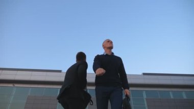 Dolly, açık havada başarılı bir iş anlaşması yaptıktan sonra evrak çantalı iki genç iş adamını dans ederken çekti. Ofis yakınlarındaki başarılarını kutlayan neşeli yöneticiler.