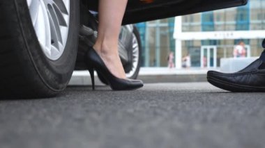 İşadamı açar ve araba güzel genç kadın için kapıyı tutar. Otomatik dışarı almak yüksek topuklu ayakkabılarla işkadını ince bacakları. Ağır çekim düşük açılı görünümü kapatın