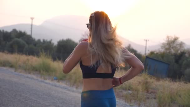 Une jeune femme s'entraîne pour le marathon en plein air. Fille sportive jogging dans la route de campagne. Mode de vie sain et actif. Ralenti Vue arrière arrière — Video