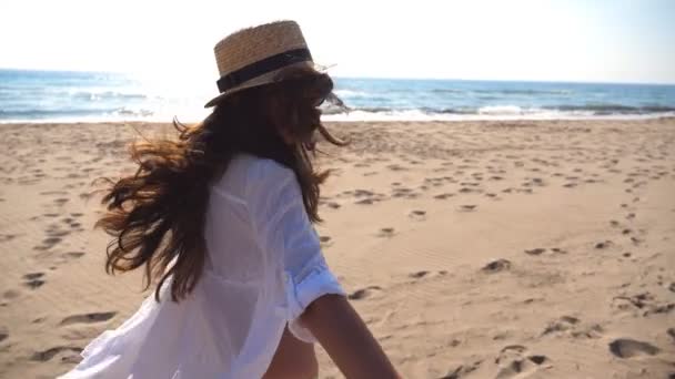 Sígueme la foto de una joven con sombrero tirando de su novio en la orilla del mar. Chica sosteniendo la mano masculina y corriendo en la playa al océano. Vacaciones de verano o concepto de vacaciones. Punto de vista POV Cámara lenta — Vídeo de stock