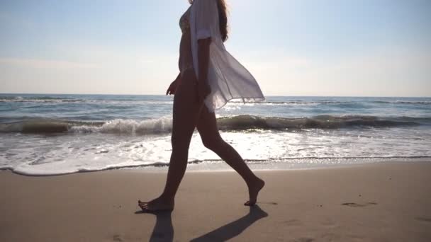 누구도 알아볼 수없는 여성 이 바다 근처 해변을 걷고 있습니다. 아름다운 소녀가 삶을 즐기고 바닷가를 걷고 있습니다. 여름 방학이나 휴가. 배경은 자연 경관. 느린 동작 — 비디오