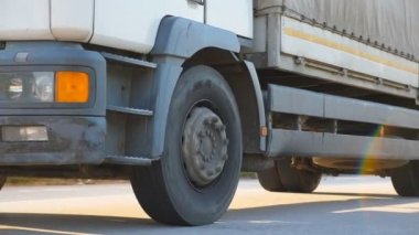 Asfaltta kamyon gezintisi. Kamera, otoyolda giden kamyonu takip ediyor. Kamyon arka planda güzel bir manzarayla kırsal alanda ilerliyor. Yan Görünüm Yavaş çekim Kapat