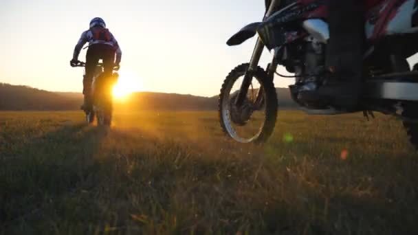 Motorradfahrer, die mit ihren Motorrädern durch weite Felder fahren. Freunde, die sich im Freien aktiv erholen und bei Sonnenuntergang leistungsstarke Motorräder fahren. Biker genießen die Fahrt. Extremsportkonzept. Landschaftliche Landschaft — Stockvideo