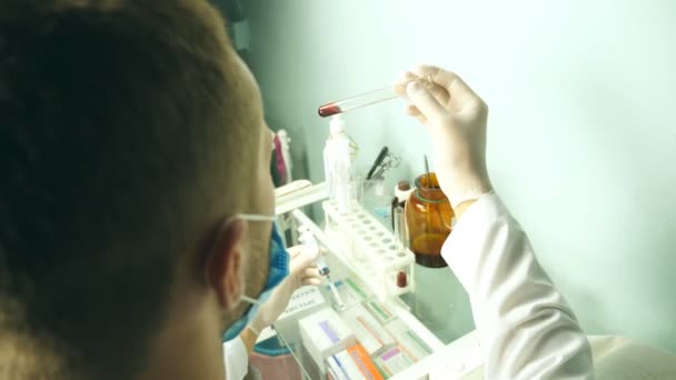 Point de vue du médecin masculin avec des gants de protection tenant une éprouvette avec du sang et des échantillons de test sur le laboratoire de l'hôpital. Prélèvement sanguin, analyse. Gros plan POV — Video