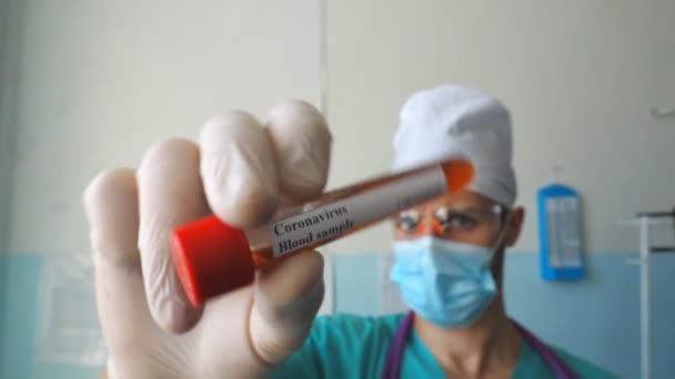 Mão de médico segurando tubo de teste com amostra de sangue para coronavírus. Braço de médico com luvas de proteção testando amostras de sangue no hospital. Conceito de vida em saúde e segurança da pandemia de COVID-19 — Vídeo de Stock