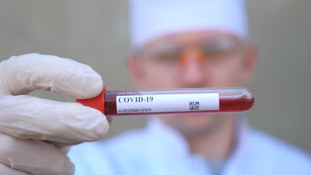 Doctor holding test tube with blood sample to coronavirus. Hand of medic with protective gloves testing blood samples on laboratory. Concept of health and safety life from COVID-19 pandemic. Close up — Stock Video