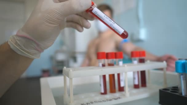 Mão de marcação médica como positiva para COVID-19 uma amostra de sangue de paciente em laboratório ou hospital. Análises laboratoriais ao vírus da Coroa. Conceito de vida de saúde e segurança da pandemia de coronavírus — Vídeo de Stock