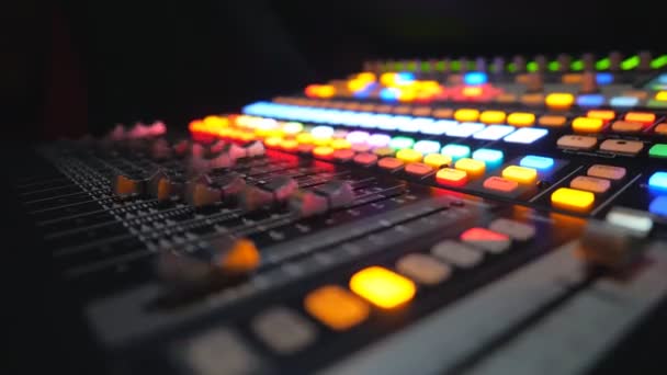 Widok z boku ruchomych przycisków na zdalnym lub soundboardzie DJ. Proces pracy w studio nagraniowym. Zamazane tło z jaskrawo świecącymi kluczami. Muzyk na nocnej imprezie. Powolny ruch Zamknij — Wideo stockowe