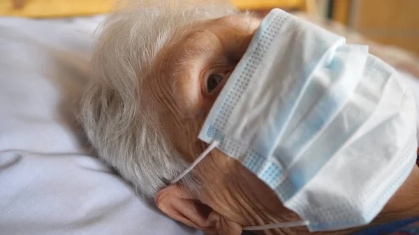 紧贴着老太婆的脸 戴着防毒面具 一位带着医疗面罩的生病女士躺在医院的病床上 健康和安全生命的概念来自于头孢病毒或大流行病 Dolly Shot — 图库照片