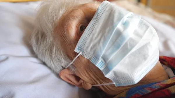 紧贴着老太婆的脸 戴着防毒面具 生病的老太太 戴着医疗面罩躺在医院的病床上 免于结肠病毒或大流行病的健康和安全生命概念 — 图库照片