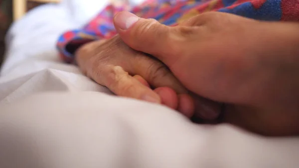 一位被诊断患有头孢病毒的老妇人躺在医院的床上 无法辨认的男人轻抚生病的母亲的手 表示爱或支持 流行病造成的健康和安全寿命概念 — 图库照片