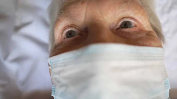 ウイルスから保護マスクを身に着けている老婦人の肖像 病院のベッドに横になった悲しい光景と医療面のマスクを持つ病気の女性 パンデミックからの健康や安全生活の概念 スローモーション — ストック写真