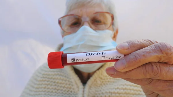 保護マスクのおばあちゃんはコロナウイルスの陽性結果で血液検査をしてる 悲しい感情を示すカメラを見て病気のおばあちゃん パンデミックからの健康と安全生活の概念 Covid — ストック写真