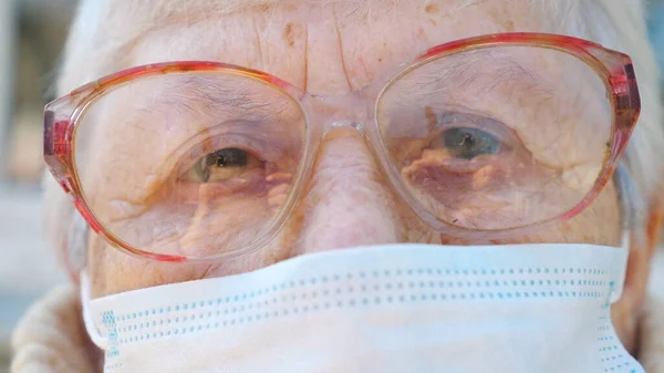 用防毒面罩捂住奶奶的脸 老太婆用沉思的目光看着照相机 流行病对健康和安全生命的影响概念 老年人用的检疫大头牛 — 图库照片