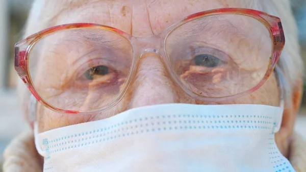 ウイルスから保護マスクのおばあちゃんの顔を閉じてください 年配の女性がカメラを覗き込んでいる パンデミックからの健康と安全の生活の概念 老人用検疫コロナウイルス — ストック写真