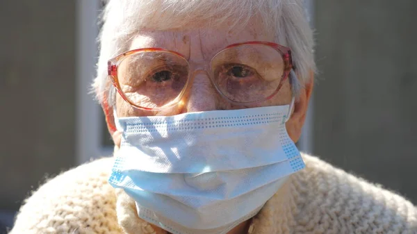ウイルスから保護マスクにおける女性の年金受給者の肖像 年配の女性は悲しい気持ちでカメラを覗き込む パンデミックからの健康と安全の生活の概念 高齢者のためのコロナウイルスの隔離 — ストック写真