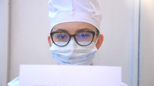 Une femme médecin tient une photo avec l'inscription rester à la maison pendant l'épidémie de coronavirus. Medic affiche montre avec un appel à l'auto-isolement. Concept de vie en sécurité contre la pandémie de COVID-19 — Video