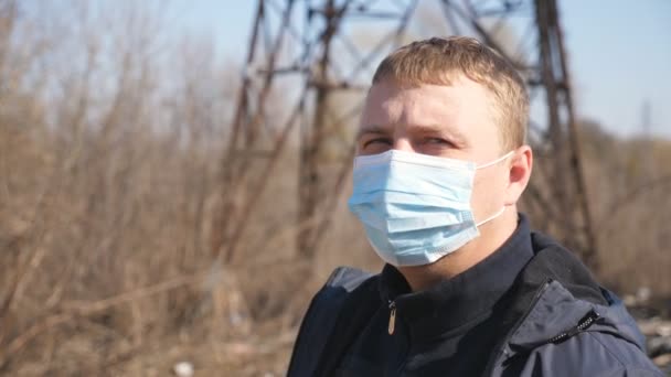 Πορτρέτο του ανθρώπου με ιατρική μάσκα πρόσωπο στέκεται στο δρόμο της πόλης κατά τη διάρκεια της επιδημίας COVID-19. Ο τύπος έβγαλε προστατευτική μάσκα από τον ιό και χαμογέλασε. Έννοια της ζωής για την υγεία και την ασφάλεια από την πανδημία του coronavirus — Αρχείο Βίντεο