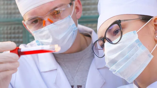 Két Orvos Vizsgálja Kémcsövet Vérmintával Koronavírushoz Férfi Női Orvosok Védőkesztyűvel — Stock Fotó