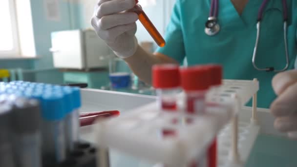 Науковець перевіряє зразки крові на COVID-19 і додає тестову трубку в стійці в лабораторії. Лікар обстежує трубку з зразком крові до коронавірусу. Концепція здорового і безпечного життя від пандемії вірусу корони — стокове відео