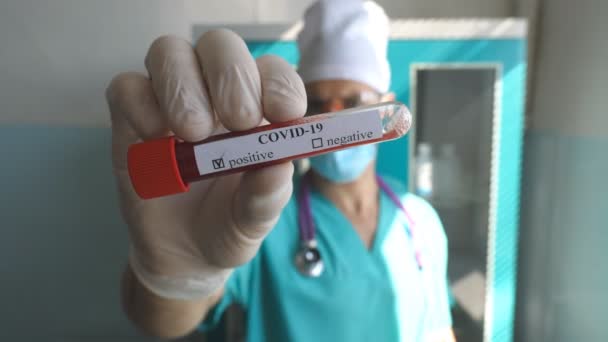 Young doctor showing test tube with blood sample to coronavirus COVID-19. Medic with protective gloves holds blood samples on hospital or laboratory. Concept of health and safety life from pandemic — Stock Video