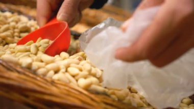 Plastik torbaya fındık toplayan erkek el görüntüsü. Tanınmayan bir adam raftan fındık alıyor. Marketten bir alıcı. Alışveriş ve sağlıklı yiyecek kavramı. Yavaş çekim. Yakın çekim.