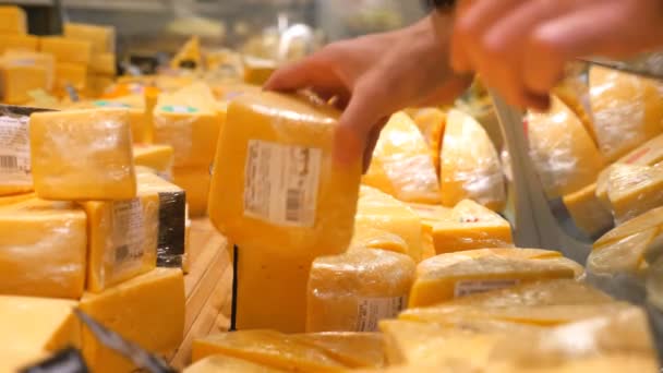 Mão fechada de consumidor masculino que toma o queijo da geladeira com a leiteria no supermercado. Homem selecionando produtos lácteos na seção refrigerada da loja. Comprador selecionando mercadorias. Conceito de compras. Movimento lento — Vídeo de Stock