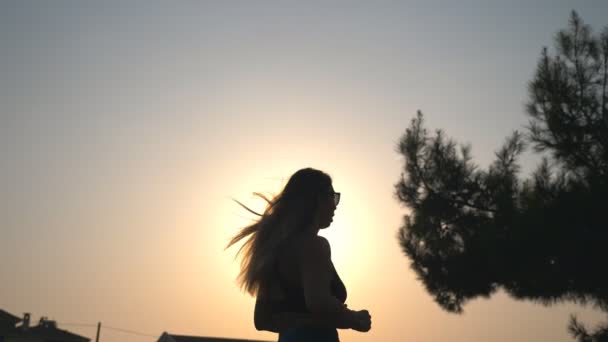 Healthy girl jogging along country road with sunset at background. Unrecognizable sporty woman working out outdoor at evening time. Female sportsman doing run training. Concept of active lifestyle — Stock Video