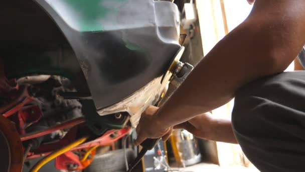 Soldador masculino pulido cuerpo del coche viejo utilizando la máquina amoladora y gafas protectoras en el taller. Reparador adulto o trabajador mecánico pulido auto con equipo profesional eléctrico en el garaje. Grúa tiro — Vídeos de Stock