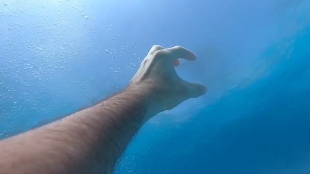 De mannelijke hand strekt zich uit van onder water tot zonnestralen. Arm vraagt om hulp en probeert naar de zon te reiken. Het standpunt van de mens die verdrinkt in de zee of oceaan en naar de oppervlakte drijft. Slow motion POV — Stockvideo