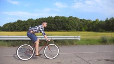 Kırsal yolda klasik bisiklete binen genç yakışıklı adam. Sportif adam pistte bisiklet sürüyor. Erkek bisikletçi otoyolda sabit vitesli bisiklet sürüyor. Sağlıklı aktif yaşam biçimi Kapat