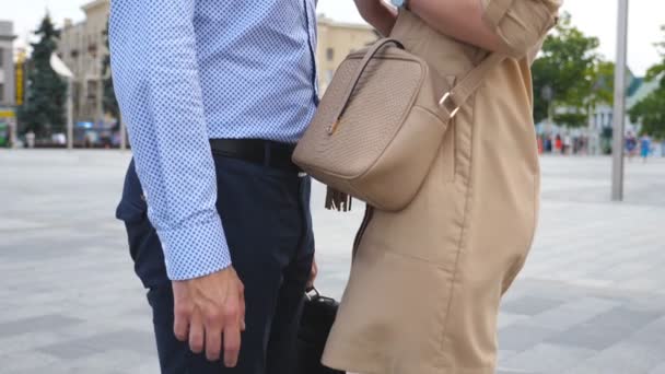 Joven hombre de negocios en ropa formal con maletín y empresaria en vestido de pie en la calle de la ciudad. Reunión de pareja de negocios en entorno urbano. Vista lateral Primer plano Cámara lenta Grúa disparada — Vídeo de stock