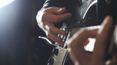 Rock müzik solosu yapan adamın elleri. Elektro gitaristin kollarını kapatın. İpleri tıngırdatan gitaristin erkek parmakları. Yetişkin adam yeni bir melodi yazıyor. Yavaş çekim