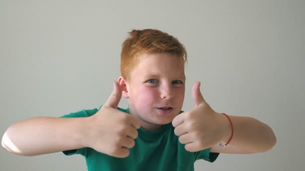 Retrato de niño pelirrojo feliz con pecas. Adorable bebé guapo animando el éxito y mostrando los pulgares hacia arriba. Acercamiento de las emociones del niño varón con expresión de alegría en la cara. Movimiento lento — Vídeo de stock