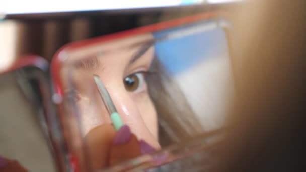 Menina de olhos castanhos jovens refletem no espelho durante a aplicação de rímel em pestanas. Mulher atraente cuidando de si mesmo fazendo maquiagem. Conceito de moda e estilo. Visualização de detalhes em câmera lenta — Vídeo de Stock