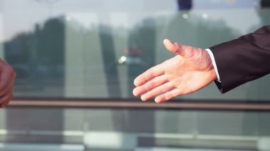 Ofis binası yakınlarında başarılı bir anlaşma yaptıktan sonra kendine güvenen iki işadamı el sıkışıyor. Şehir ortamında birbirlerini tebrik eden genç meslektaşlar. İş ortaklarının el sıkışması. Yavaş çekim