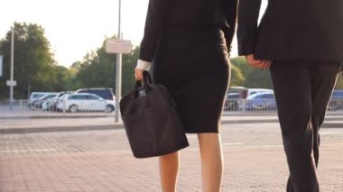 İş adamları havaalanından ayrılıp valizleriyle şehir caddesinde yürüyorlar. Terminalden inip tekerlekli bavulu yuvarlayan topuklu ayakkabı giymiş tanınmayan bir adam ve kadın. İş gezisi kavramı. Yavaş çekim