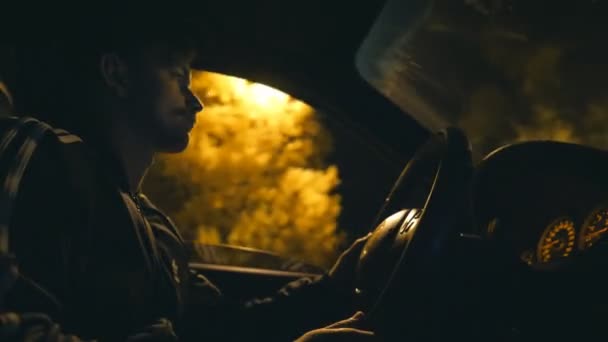 Male driver holds hands on steering wheel and rides in auto on highway at night time. Guy drives a modern automobile at evening. Young man moves in his SUV car on empty road. Close up — Stock Video