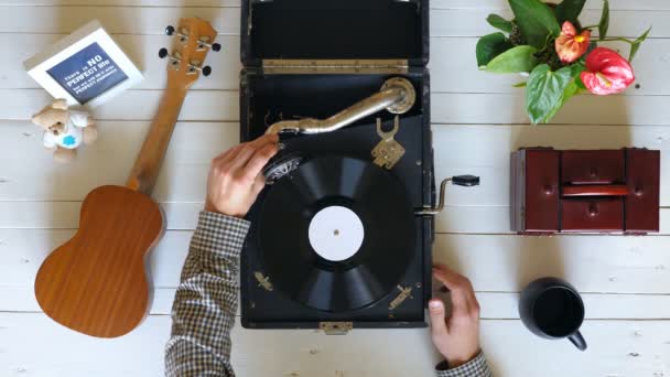 Man putting stylus with needle on vinyl record. Top view on male hands turning on vintage gramophone at white table background. Retro concept. Above shot Slow motion Close up — Stock Video