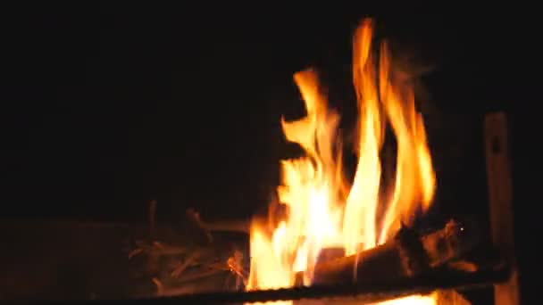 Hermosas llamas se eleva de la quema de rebanadas de madera y carbón vegetal en mangal por la noche. Leña y carbón se queman en barbacoa sobre fondo negro. Concepto de calidez y tranquilidad. Primer plano: cámara lenta — Vídeos de Stock