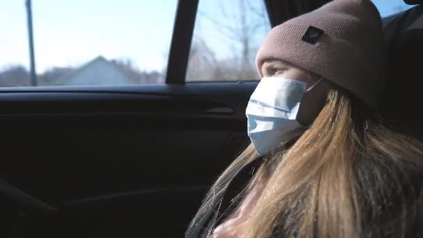 Menina com máscara médica viajando de carro e olhando pela janela. Criança triste usando máscara protetora do vírus durante o passeio. Conceito de vida de segurança da pandemia de coronavírus — Vídeo de Stock
