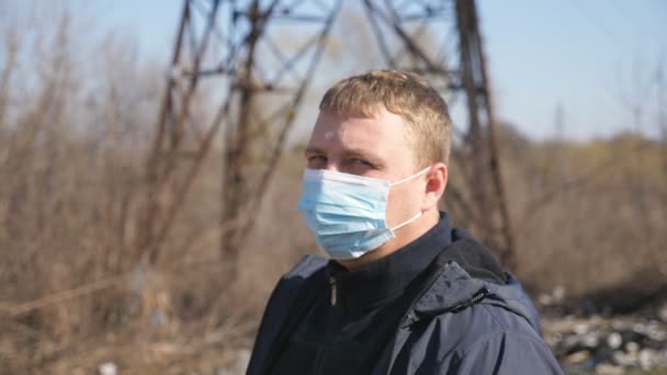 Πορτρέτο του ανθρώπου με ιατρική μάσκα πρόσωπο στέκεται στο δρόμο της πόλης κατά τη διάρκεια της επιδημίας COVID-19. Ο τύπος φοράει προστατευτική μάσκα από τον έξω κόσμο του ιού. Έννοια της ζωής για την υγεία και την ασφάλεια από την πανδημία του coronavirus — Αρχείο Βίντεο