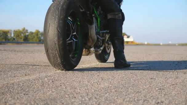 Biker is sitting on his motorcycle at highway and starting ride. Man begin riding a motorbike at country road. Concept of freedom and adventure. Rear view — Stock Video