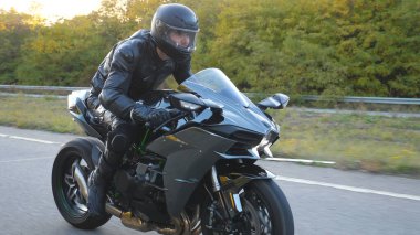 Otobanda modern spor motosiklet kullanan kasklı genç adamı yakından çek. Motosikletli, kır yolunda motosikletiyle yarışıyor. Yolculuk sırasında bisiklet süren adam. Özgürlük kavramı. Yan görünüm Yavaş çekim.