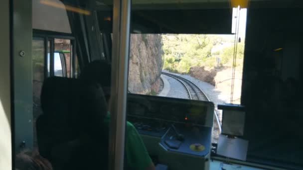認識できない列車の運転手が山岳道路の間で電気列車を運転する。運転室から鉄道線路への眺めのポイント。リアバックビューPOVスローモーションクローズアップ — ストック動画