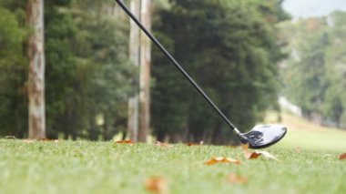 Erkek golfçü golf sahasında topa vuruyor. Çarpışmadan sonra yeşil çimen parçacıkları havaya yükselir. Boş zaman ve eğlence kavramı işte. Düşük görünüm Yavaş çekim